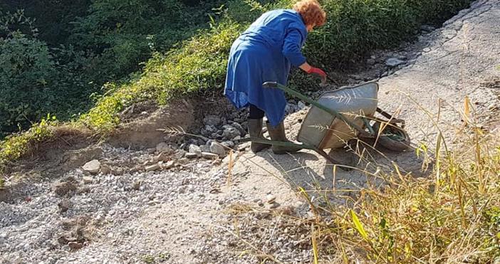 Възрастна жена сама пълни дупките и ремонтира пътя до дома